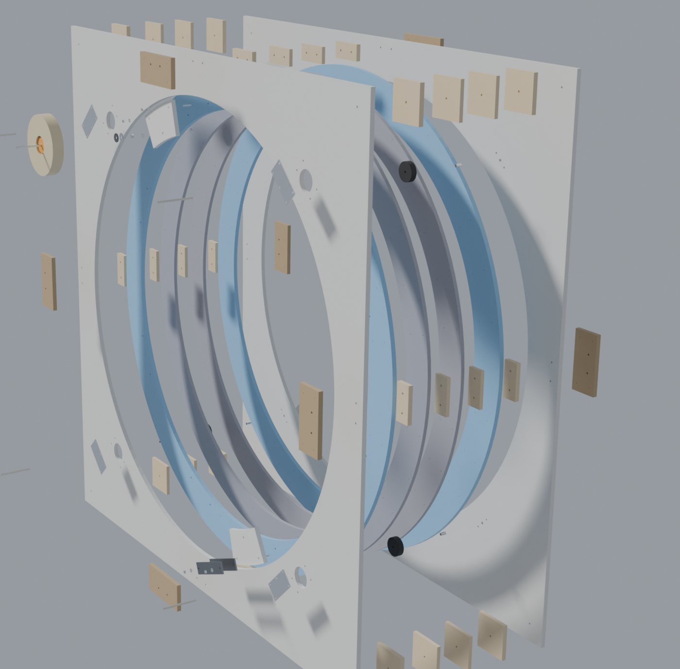 A computer rendering of a large machine pulled apart along its axis: two big square panels, four ring layers between them, dozens of small spacer blocks floating in rows, two black wheels, and a roll of tape off to one side